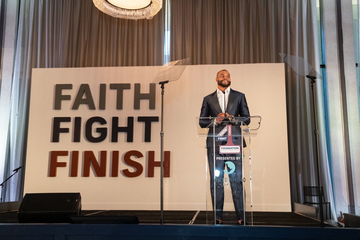 person giving a speech with the faith struggle logo in the background